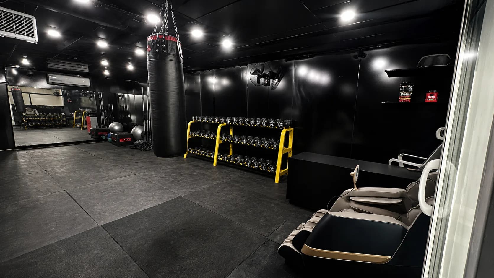 The black and yellow SyK training floor with open exercise space and equipment